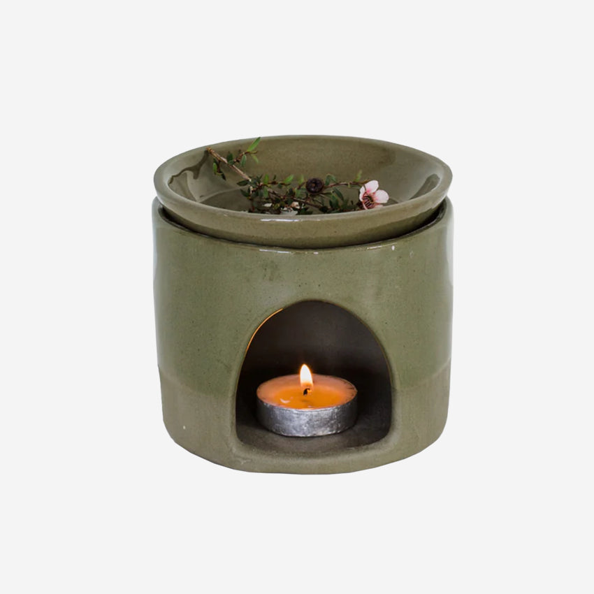 The JS Ceramics Ceramic Oil Burner in Sage Green with Manuka in it and candle in the bottom on a blank background
