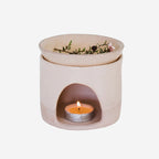 The JS Ceramics Ceramic Oil Burner in Pink Sand with Manuka in it and candle in the bottom on a blank background