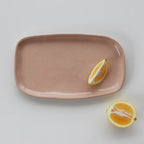 The JS Ceramics Rectangle Platter in Pink Sand with lemon slices on it on a blank background