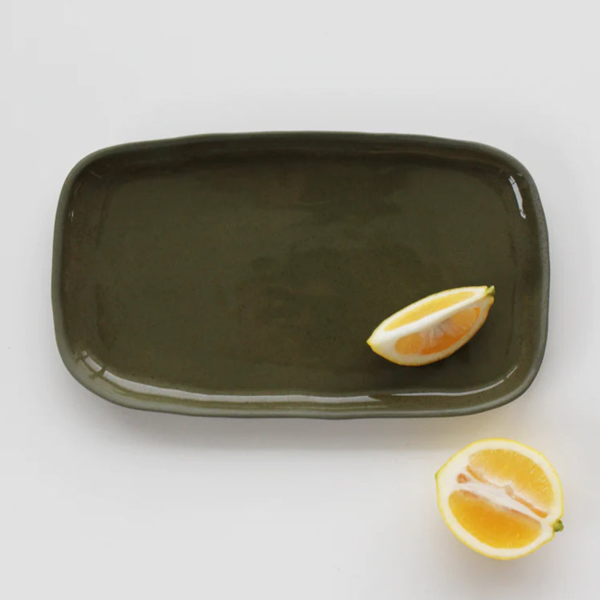 The JS Ceramics Rectangle Platter in Sage Green with lemon slices on it on a blank background