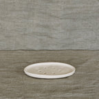 The JS Ceramics Soap Dish in Oatmeal on a green linen backdrop