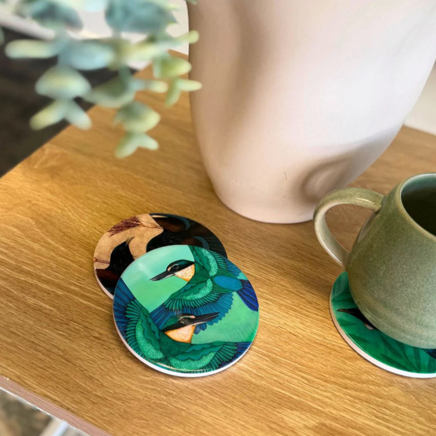 Three of the Kathryn Furniss Coasters on a table, one with a mug on it