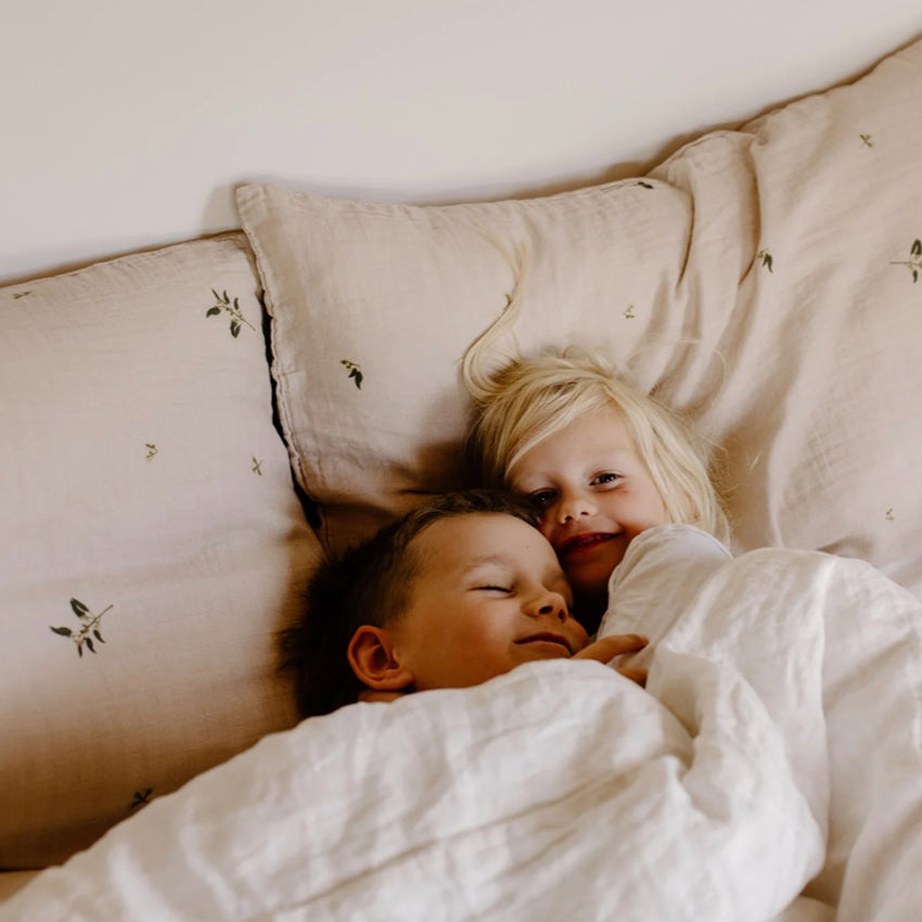 Leni The Label Muslin Pillowcase in Gum on a bed with two kids