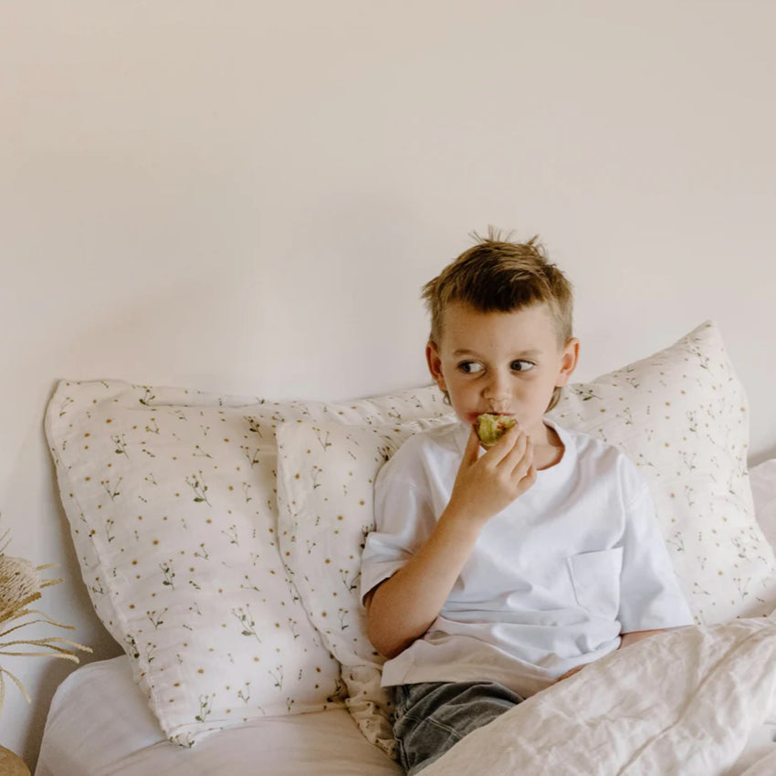 Leni The Label Muslin Pillowcase in Daisy on a bed with a boy sitting in the bed