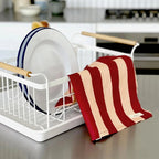 The Lettuce Linen Tea Towel in Peach and Burgundy Bold Stripe in a kitchen hanging over a Yamazaki dish rack