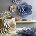 The Lovi 3D Flower Decor in Natural hanging on a wall and propped up on a basket surronded by other coloured 3D Flowers.