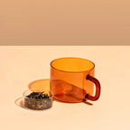 The Maho Cha Mug in Amber next to loose leaf tea