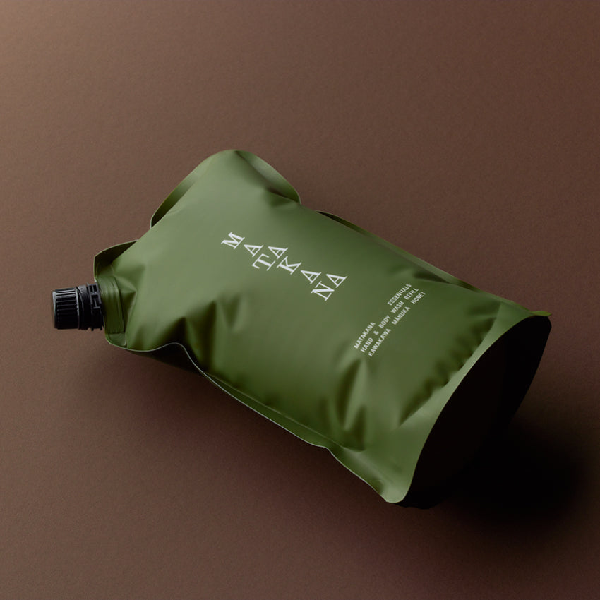 The Matakana Essentials Hand and Body Wash refill pouch lying down on a brown background