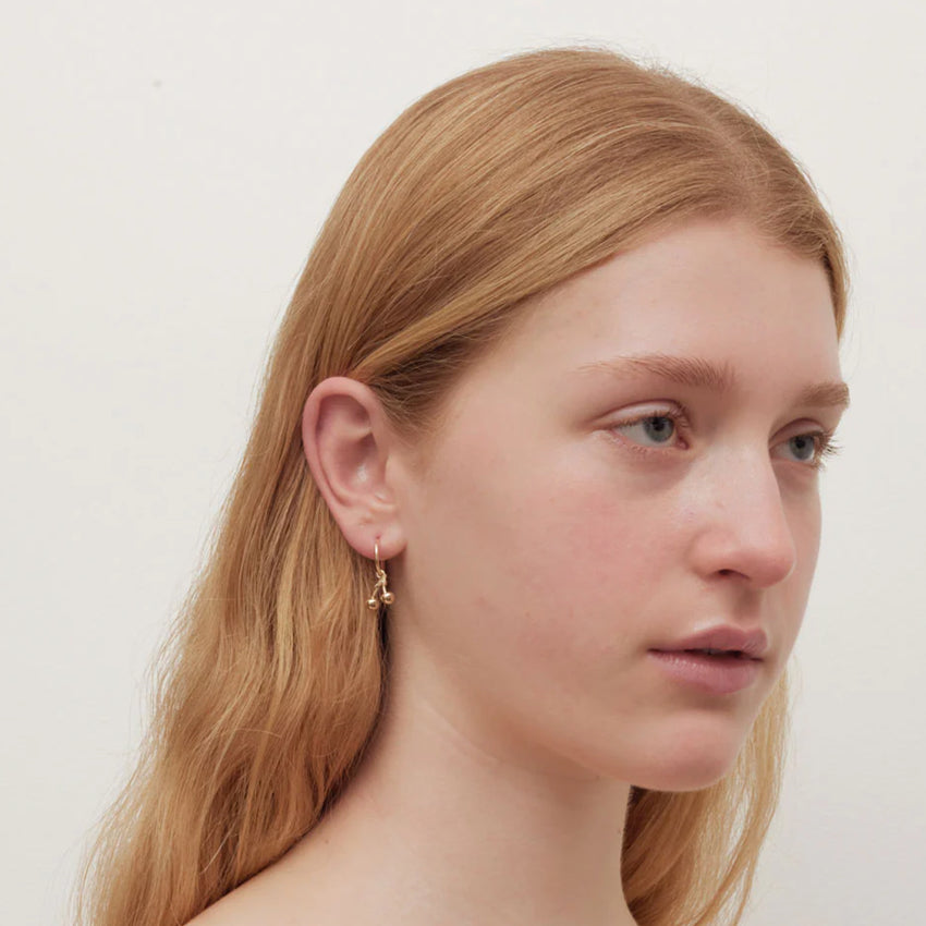 The Meadowlark Cherry Signature Hoops in gold on a model