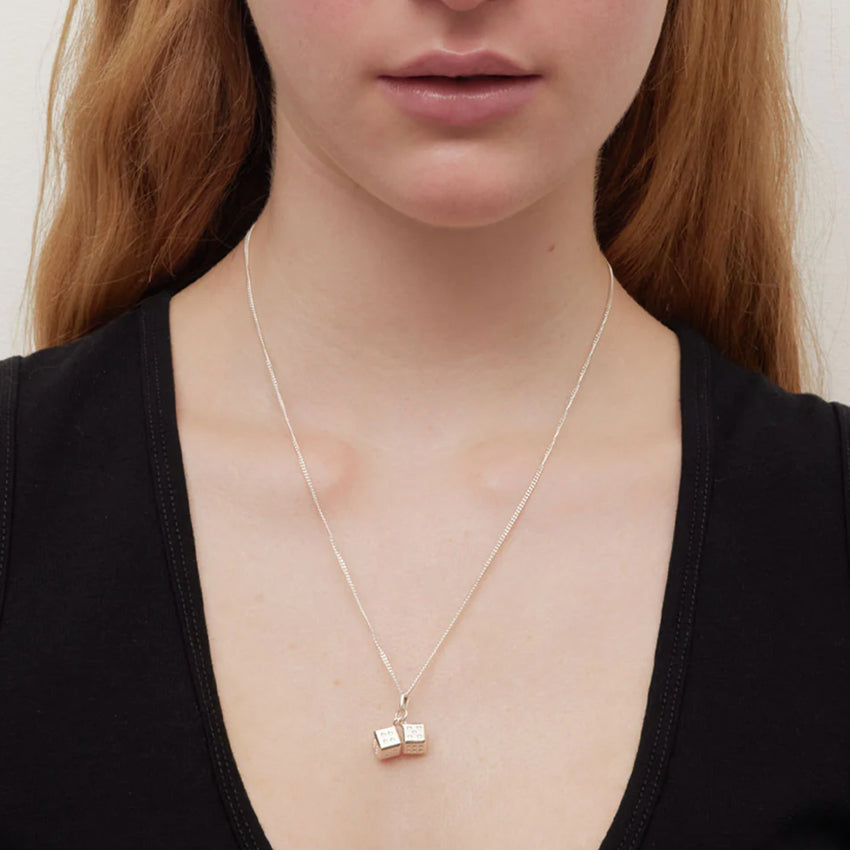 The Meadowlark Dice Charm Necklace in gold on a 50cm chain on a model