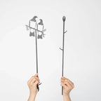 The Metalbird Kereru Pair Plant Stake separated with hands holding them on a blank background