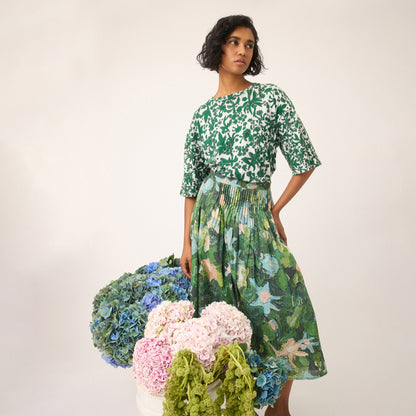 The Nancybird Alma Yoke Skirt in Garden Print on a model behind bunches of flowers