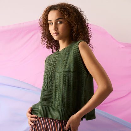 Nancybird Billie Cable Vest in Cypress Green on a model with pink and blue fabric behind her.