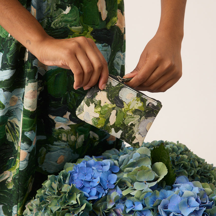 A model holding the Nancybird Garden Card Purse over a bunch of flowers