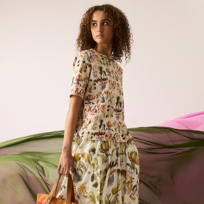 The Nancybird Grace Tee in Warm Watercolour on a model with matching skirt with fabric behind her