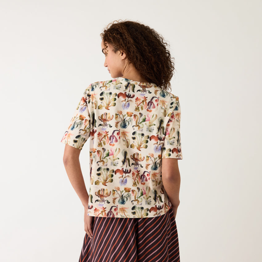A back view of the Nancybird Grace Tee in Warm Watercolour on a model on a grey background