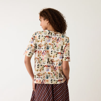 A back view of the Nancybird Grace Tee in Warm Watercolour on a model on a grey background