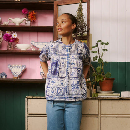 The Nancybird Gwen Blouse in Lyon Tile on a model infront of a shelf and bench