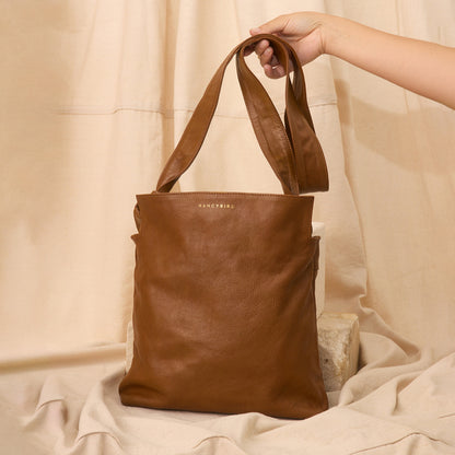 The Nancybird Shiki Bag in Tapenade with the strap being held up with a cloth background