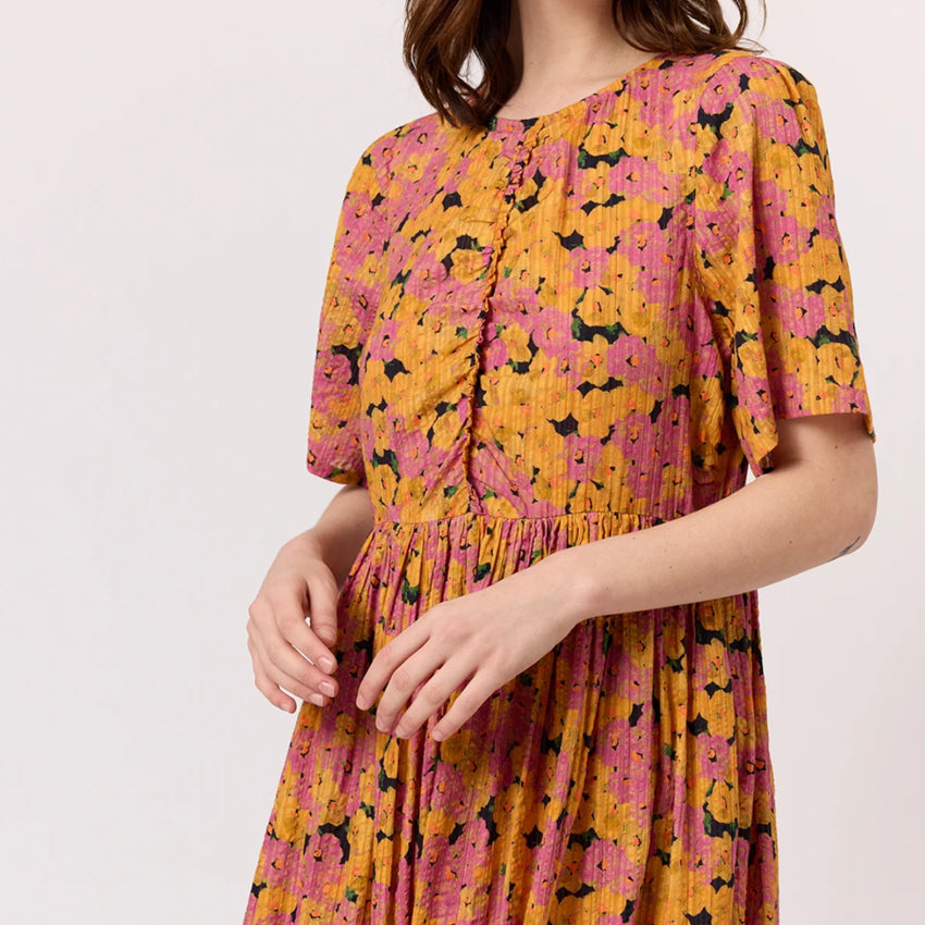 A closeup of the Nancybird Alba Dress in Sunset Floral on a model on a blank background