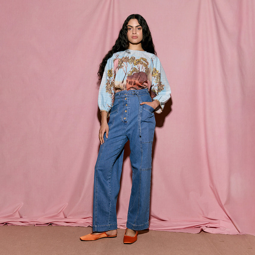 The Nancybird Amos Pant in Denim on a model on a pink background