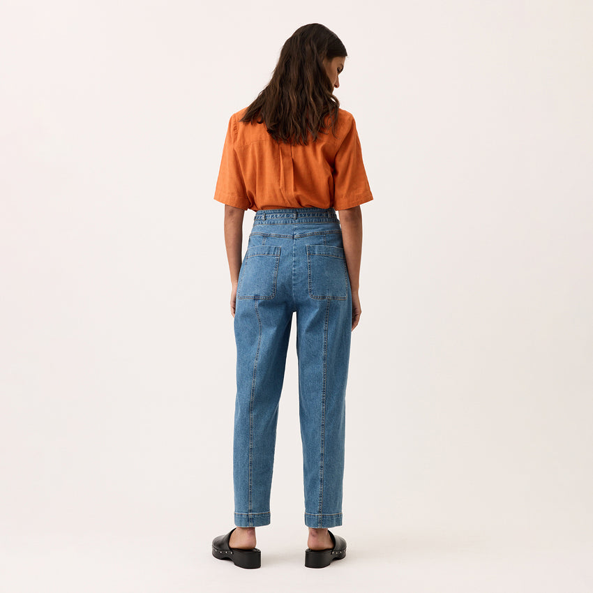 A back view of the Nancybird Amos Pant in Denim on a model on a blank background