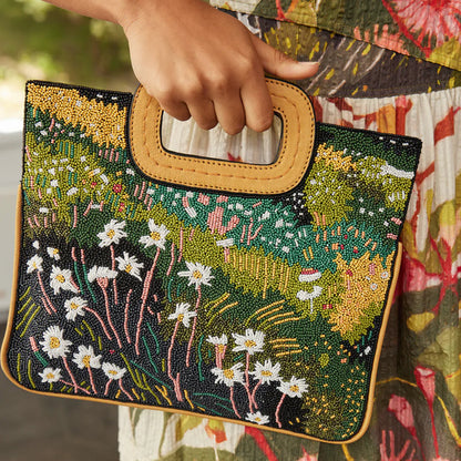 A closeup of a model holding up the Nancybird Beaded Clutch in Daisy Field 