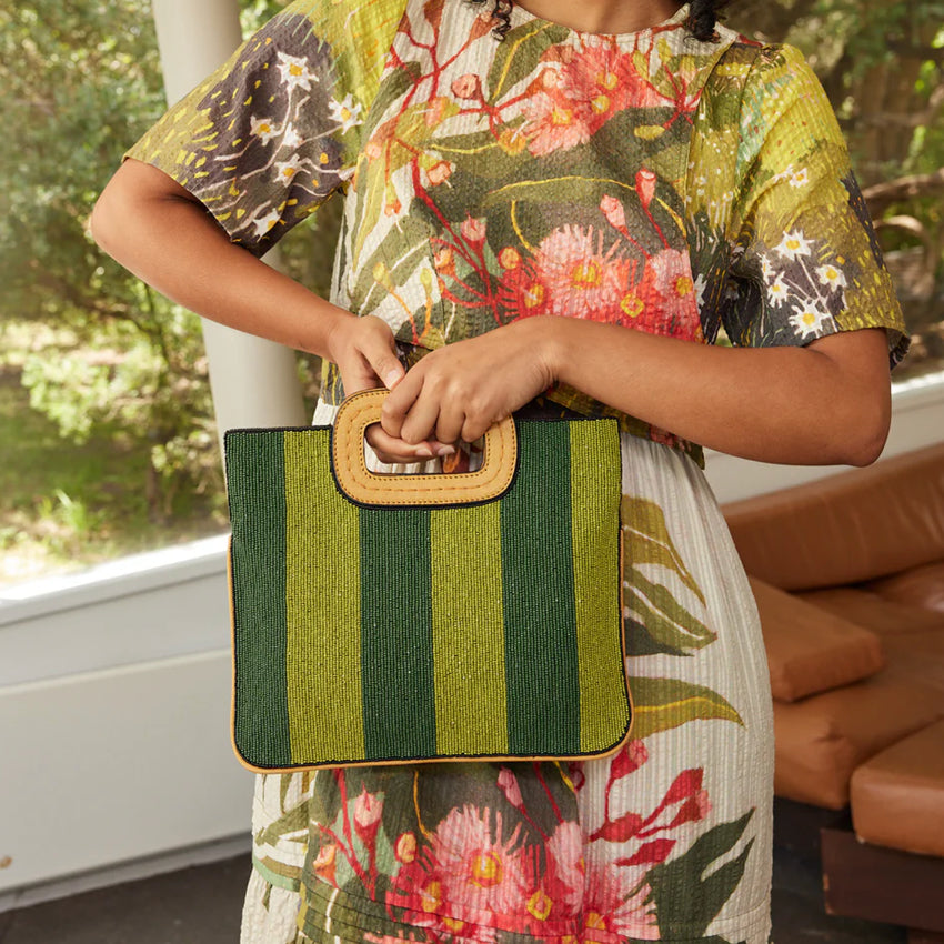 A model holding up the Nancybird Beaded Clutch in Daisy Field on the striped side