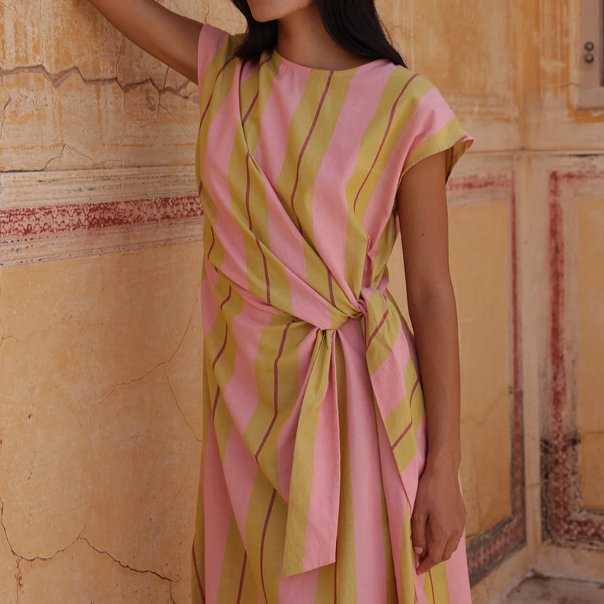 A closeup shot of the Nancybird Cacey Dress in Dusk Stripe on a model in front of a cracked wall