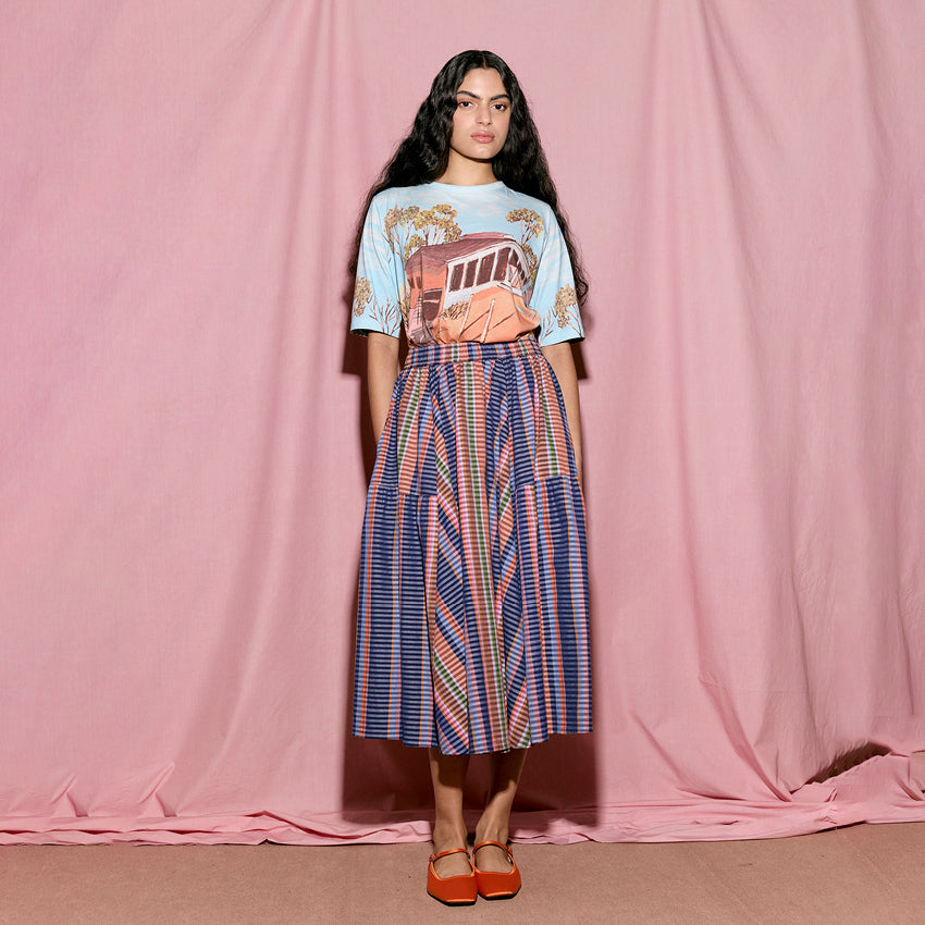 The Nancybird Eula Skirt in Line Check on a model with a pink sheet background