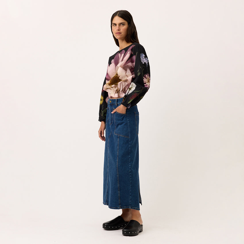 A side view of the Nancybird Franny Skirt in Denim on a model with a blank background