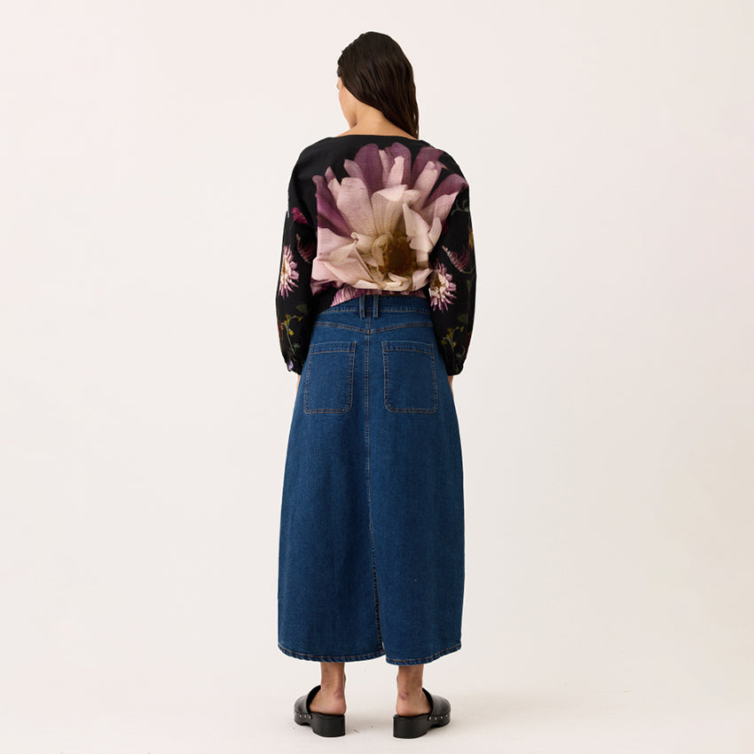 A back view of the Nancybird Franny Skirt in Denim on a model with a blank background