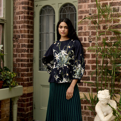 The Nancybird Mabel Top in Still Life on a model with brick and a door behind her