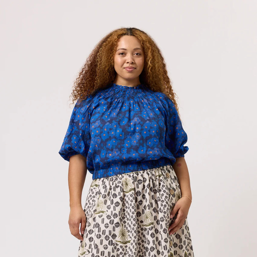 The Nancybird Maha Top in Midnight Floral on a model paired with a skirt on a blank background