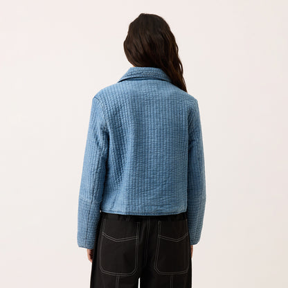 A back view of the Nancybird Nadia Quilted Jacket in Denim on a model on a blank background