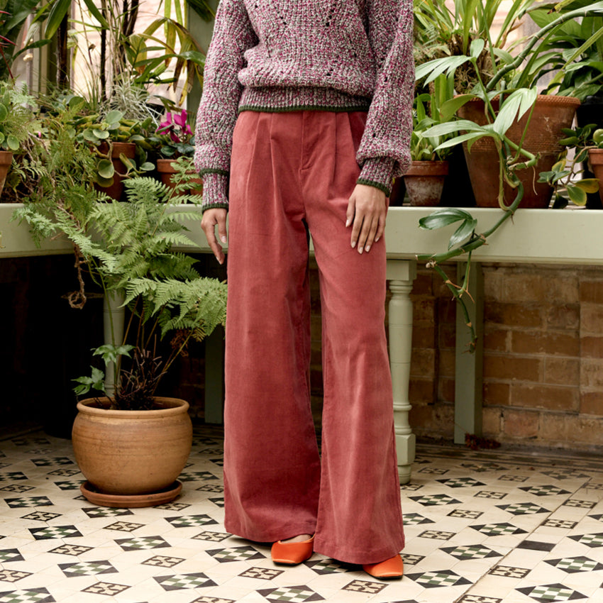 The Nancybird Niko Pants in Spice on a model in a green house