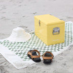 The Napoleon Goods Chilly Bin in Lemon Yellow on a towel on a beach
