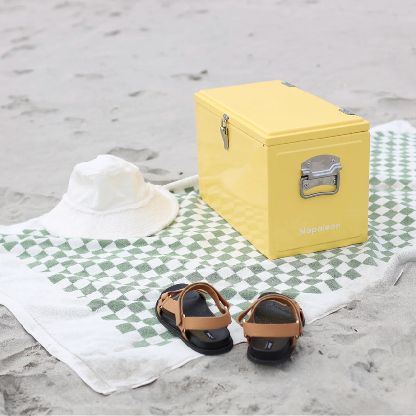 The Napoleon Goods Chilly Bin in Lemon Yellow on a towel on a beach