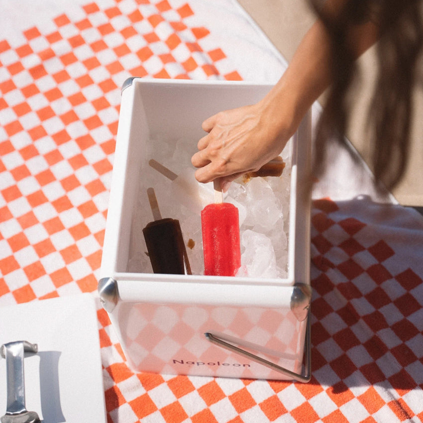 The Napoleon Goods Mini Chilly Bin in Coconut White with ice and ice blocks in it on a towel 