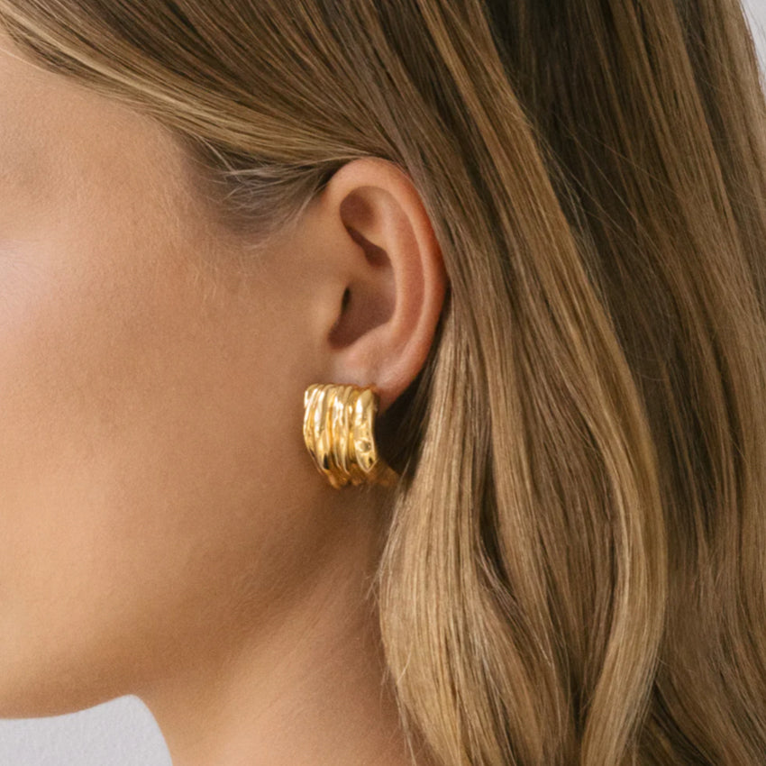 The Nina Gordon Vertigo Earrings in Gold on a model