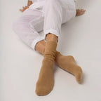 Person wearing white pants and beige Hamilton Possum and Merino Wool socks on a light background