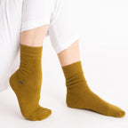 Person wearing mustard yellow Nooan Hamilton Possum and Merino Wool socks on a white background