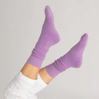Lilac Nooan Hamilton Possum and Merino Wool socks worn with white pants on a light gray background
