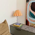 The Paola and Joy Cora Table Lamp in Tropical Peach and Purple on a console table with books and artwork
