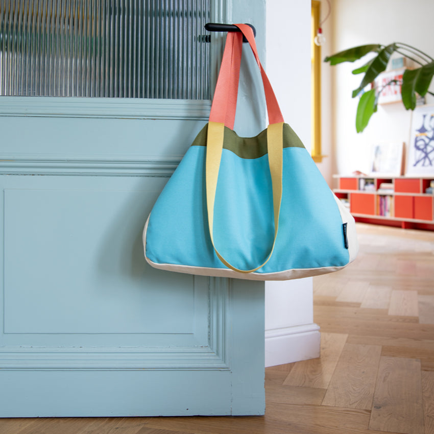 The Remember Canvas Bag in Luca colourway hanging on a blue door