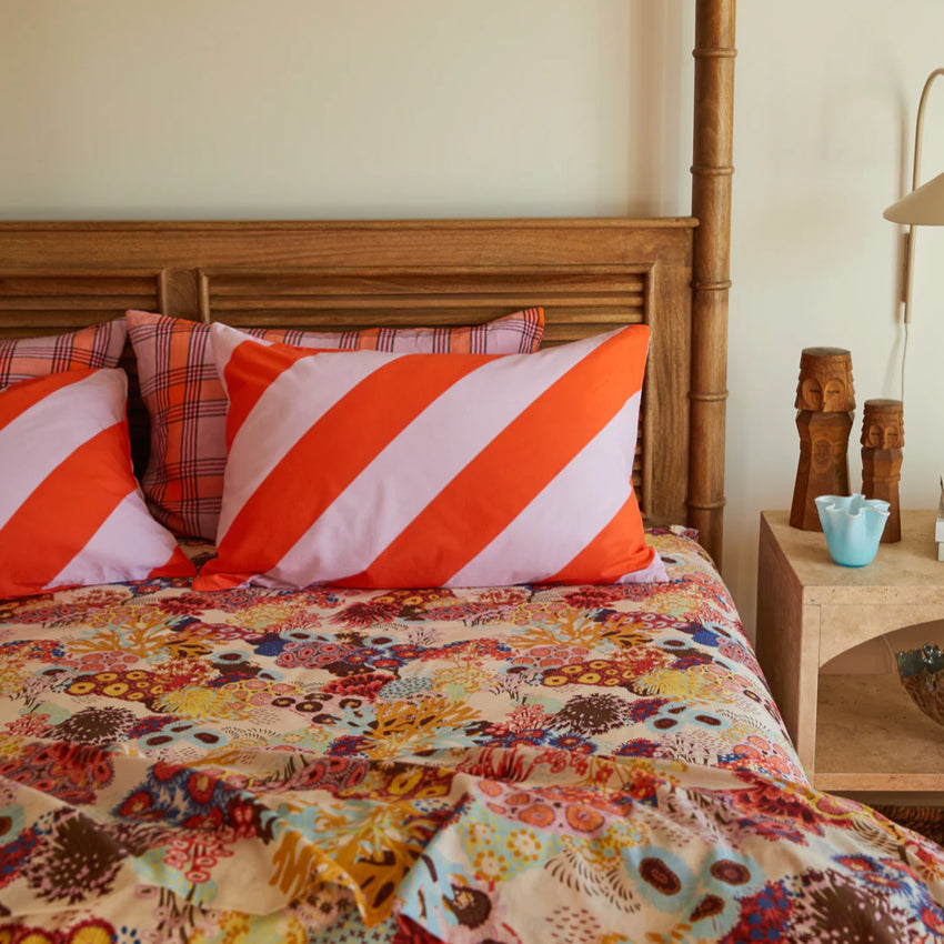 The Sage x Clare Clarice Cotton Pillowcase on a bed with other sheets and pillows