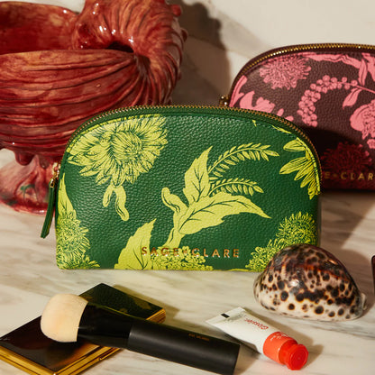 The Sage x Clare Delphine Cosmetic Pouch in Anise on a marble bench with shells and makeup next to it