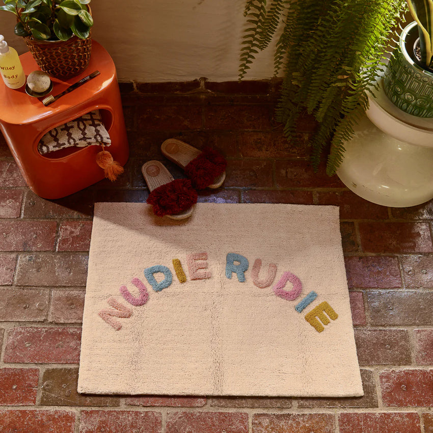 The Sage x Clare Tula Nudie Rudie Bath Mat in Tigre on a brick floor