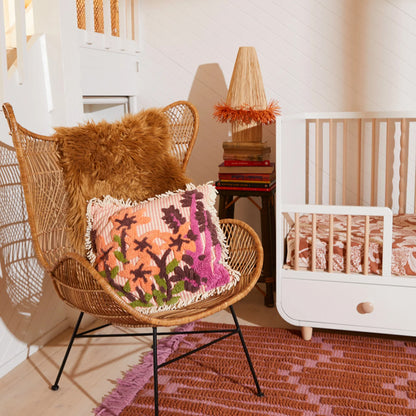 The Sage x Clare Sara Tufted Cushion on a chair next to a cot