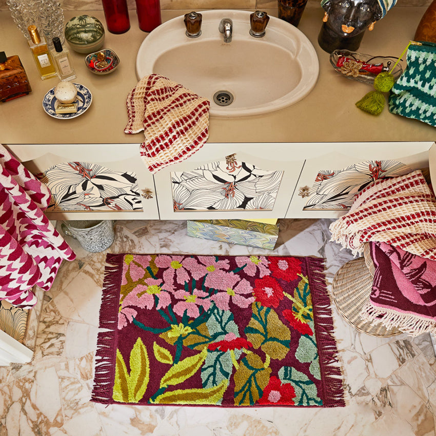 The Sage x Clare Genevieve Bath Mat in Mahogany in front of a bathroom vanity